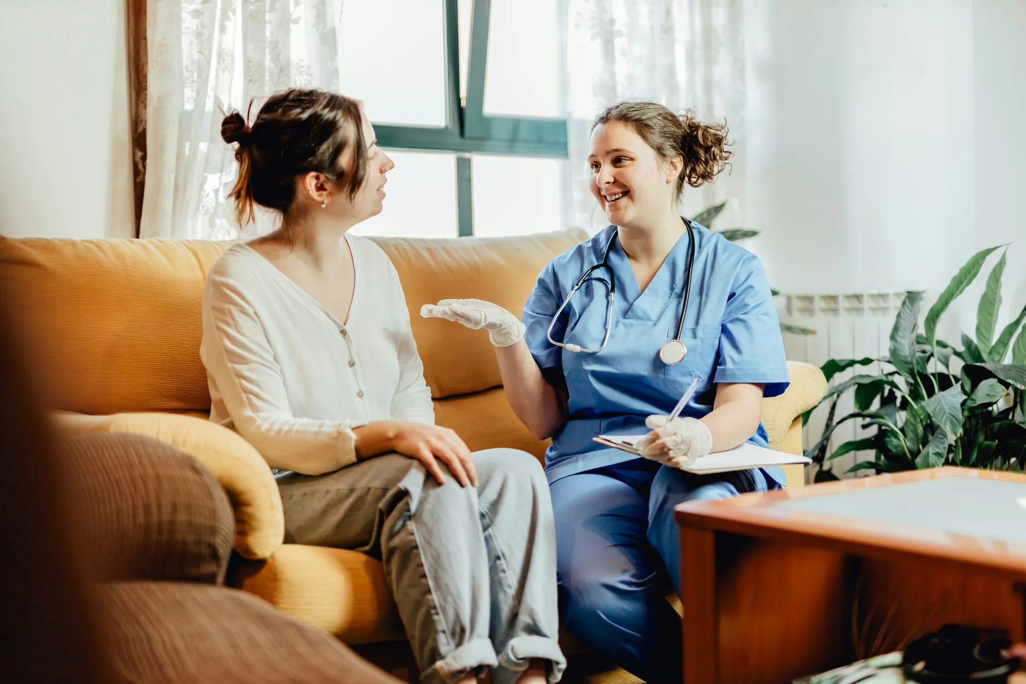 Zorgverlener in gesprek met een cliënt op de bank